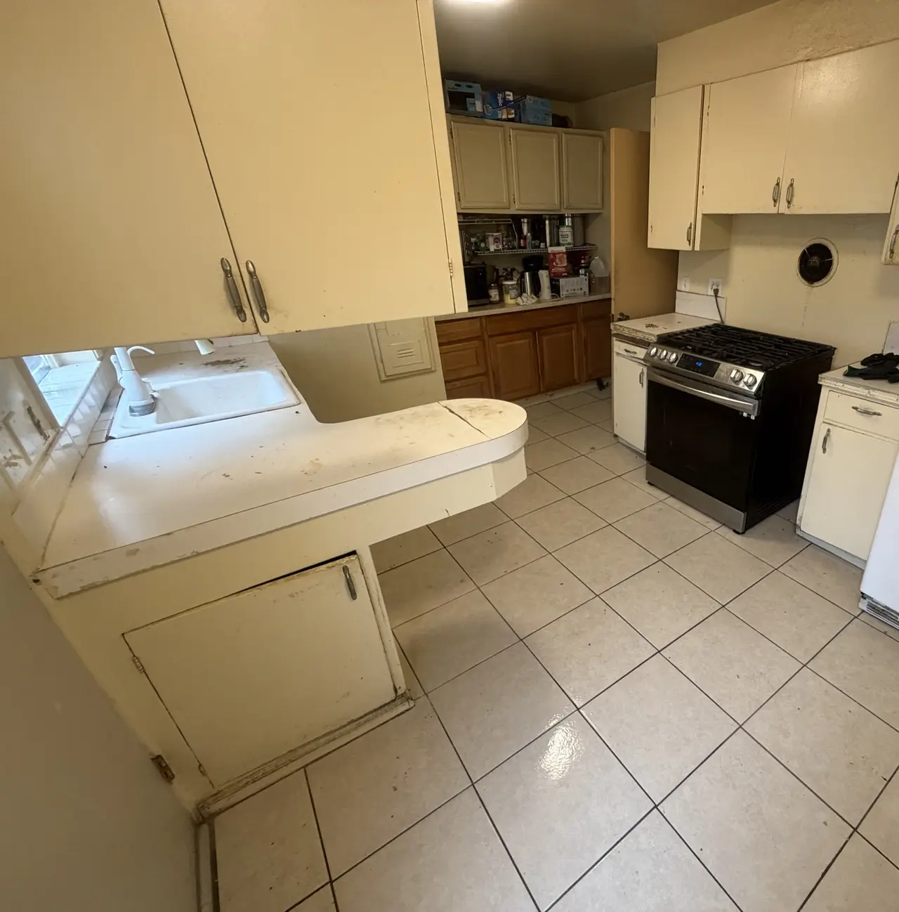 Kitchen before work began — original painted cabinets, tile counter and tile floor