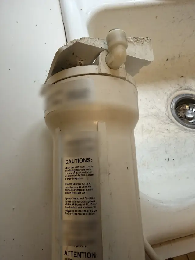 Close-up of the filter housing, sediment visible around the cap