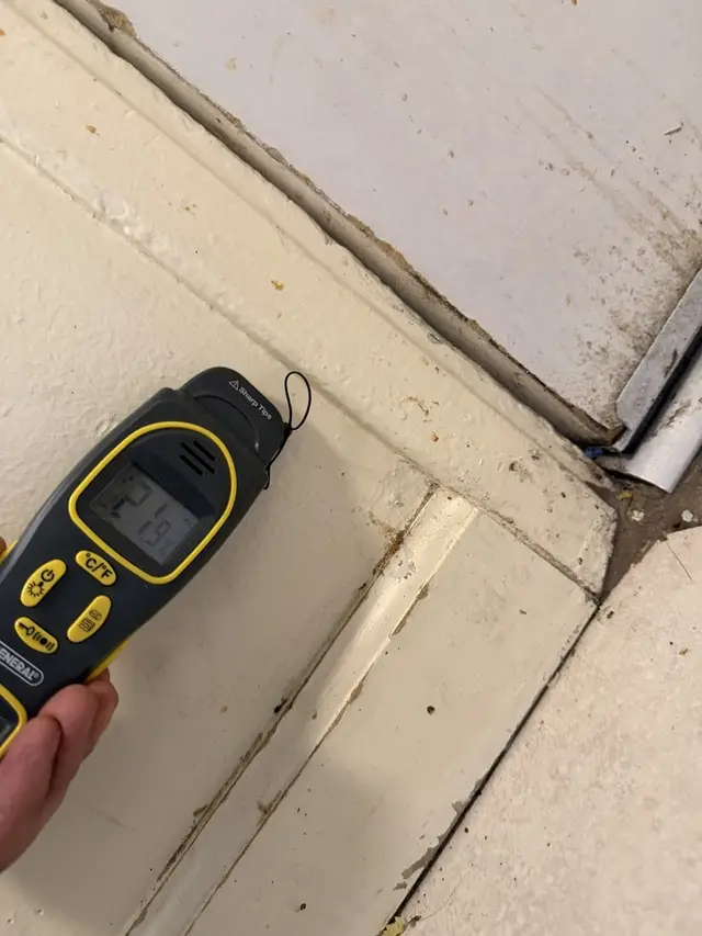 Moisture meter at the base of the kitchen back-door casing